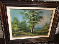 Frontal view of the signed landscape painting showing detailed view of trees, sky, and frame.