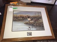 Framed signed and numbered print of Canada geese with small stamp medallion beneath the print.
