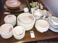 Overall view showing multiple pieces of the porcelain china set spread out on table, including plates, cups, teapot, and bowls.