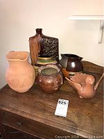 Overview photo of collection including large terra cotta pitcher, bird candle holder, pottery flask, and planters.