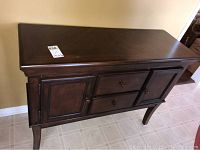 Full front and side angle view of dark wood storage table showing drawers and cabinet doors.