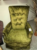 Front view of vintage olive-green upholstered chair with padded arms showing some stains and wear.