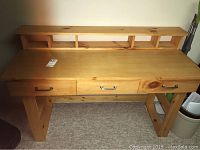 Front view of the pine wood desk showing the three drawers and top shelf with compartments.
