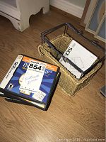 Seven Nintendo DS game cases including Brain Age, Brain Age 2, Big Brain Academy, 50 Classic Games, with instruction manuals in a woven basket nearby.