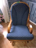 Full front view of gliding rocking chair showing wooden frame and blue upholstered cushion with small dotted pattern.