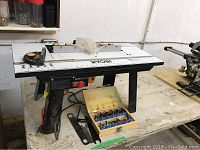 Ryobi router table setup with router mounted underneath and router bit set and wrench displayed in front on the workbench.