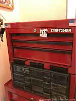 Front view of the red Craftsman metal tool box showing multiple drawers and clear bins containing screws.