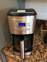 Full view of the Cuisinart coffee maker featuring stainless steel front, digital display, and glass carafe with handle.