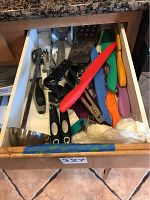 Top view of drawer containing colorful handle Cuisinart knives, spatula, meat tenderizer, and various kitchen tools.