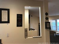 View of six wood wall art pieces hung on the wall in a living room area, showing different inspirational quotes and designs, including a key design box.