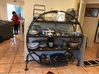 Wide view of metal shelving unit with wooden shelves filled with various household items, showing the overall condition and structure