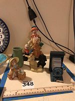 Overview photo of the Kodak camera, clown figurine, green vase, and several other decorative figurines on a table with measuring ruler showing approximate sizes.