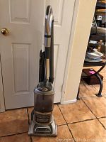 Front view of the Shark Lift-Away Deluxe vacuum cleaner showing silver and black body, clear dust cup, and cord wrapped on the back.