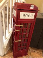 Red London phone booth style DVD holder from angled front showing sealed door.