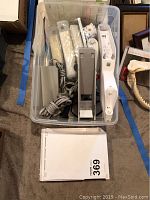 Nintendo Wii console in white with normal signs of wear. Included are power adapter, multiple Wii remotes and accessories stored in a plastic container.