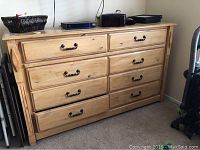 Full front view showing all eight drawers and pine finish with metal handles.