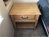Photo of one pine finish nightstand showing contemporary style with drawer and open bottom shelf, placed beside bed.