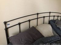 Black metal king size headboard mounted against wall with pillows and bedding for size reference.