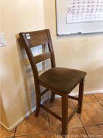 Side view of one tall wooden dining chair with brown cushioned seat showing legs and backrest design.