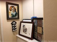 Framed clown artwork by Robert Gentry, wooden holder with six ceramic shot glasses, a framed clown art piece by Kalman, and a decorative wall hanging all arranged together