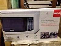 Front of the RCA microwave box displaying the unit and key features including 0.7 cubic feet capacity and 700 watts power.
