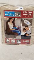 Packaged Arctic Sky heated throw blanket with label showing 50 x 60 inch size, 4 heat settings, and remote control image.