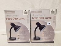 Photo of two boxed Simple Designs Basic Desk Lamps, showing full packaging front with brand and model information