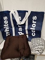 Photo showing laundry hamper bag, brown chair pad, and iron board cover