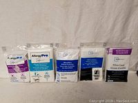 Photo shows five new queen size pillow covers in original packaging, two AllergyPro Mainstays branded pillow covers with bed bug and allergy waterproof protection, plus others made from microfibre and cotton.