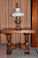 Oil lamp sitting on top of the wooden table against a curtain background