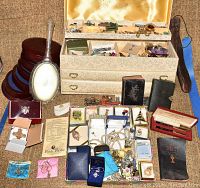 Wide shot of jewelry chest open with top tray items and loose jewelry boxes and books arranged below