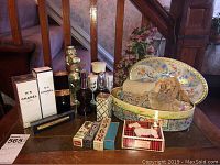 Photo of Chanel perfumes, sewing kit tin, vintage boxes, and floral decoration on table.