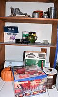 Shelf with various kitchen items including Black & Decker electric single burner, kitchen containers, burger press, and boxed pasta pot