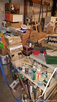 Full view of assorted stacked boxes, tools, and storage containers in a basement setting.
