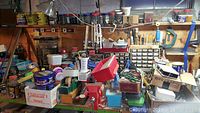 Wide view of workshop area showing many labeled boxes, hand tools, and containers on shelves and benches