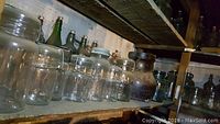 Shelf with clear mason jars and glass bottles including Ball and others.