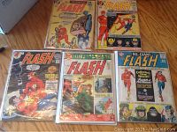 Front covers of five large vintage Flash comic books displaying colorful classic comic art.