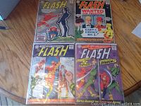 Four Silver Age Flash comic books laid on a wooden floor showing front covers of issues 151, 156, 157, 158.