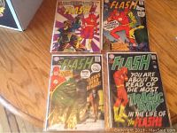 Lot of four Silver Age Flash comic books laid out on wood floor showing their covers. Issues 181 to 184, all with DC Comics branding and classic colorful artwork.