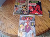 Three Silver Age Flash comic books laid out on a table, showing covers for issues #161, #163, and #165.