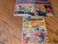 Three comic books laid on a wooden surface, titles including Laugh and Stanley, showing colorful cartoon covers.