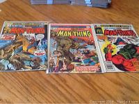 Set of three Man-Thing comics (issues 11, 13, 14) displayed on a wooden surface