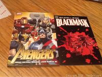 Front covers of The Avengers and Black Mask graphic novels laid flat on wooden surface.