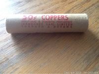 Photo of a closed paper bank roll labelled '50¢ COPPERS' and 'Armoured Car Limited Toronto & Ottawa' lying on wood surface.