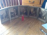 Set of 5 framed black and white antique prints arranged in a semi circle on a wooden table.