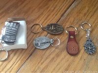 Lot of 5 assorted key chains arranged on a wooden surface.