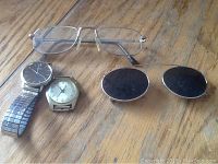 Top-down view showing the Sutton eyeglasses, sunglasses, and two watches on wooden surface.
