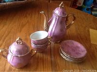 Full set including teapot, creamer, three cups, and six plates on wooden table