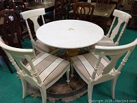 White round table with stone top and four upholstered chairs around it, showing full set.
