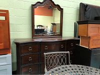 Full view of dark wood dresser with attached mirror in scalloped frame.
